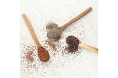 Three spoons with different types of seeds laying next to each other.